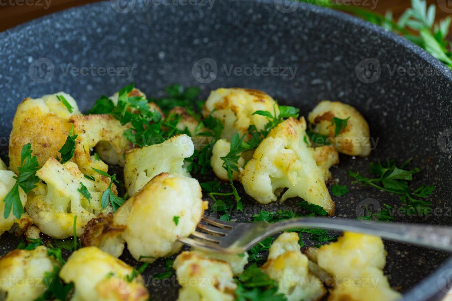 Fried cauliflower with spices and herbs in a frying pan photo