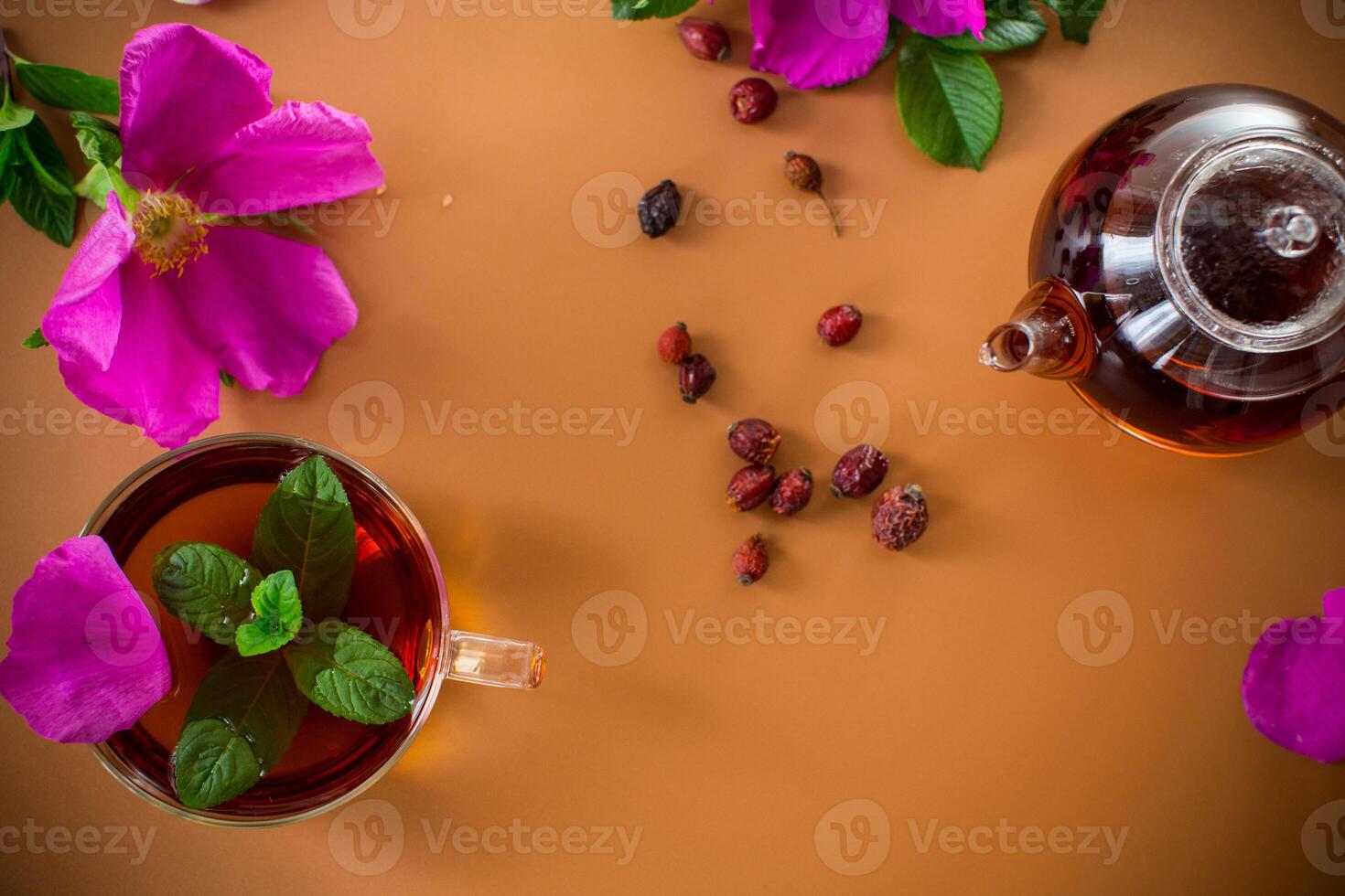 Top view of brewed rosehip tea with mint in glassware on brown background. photo