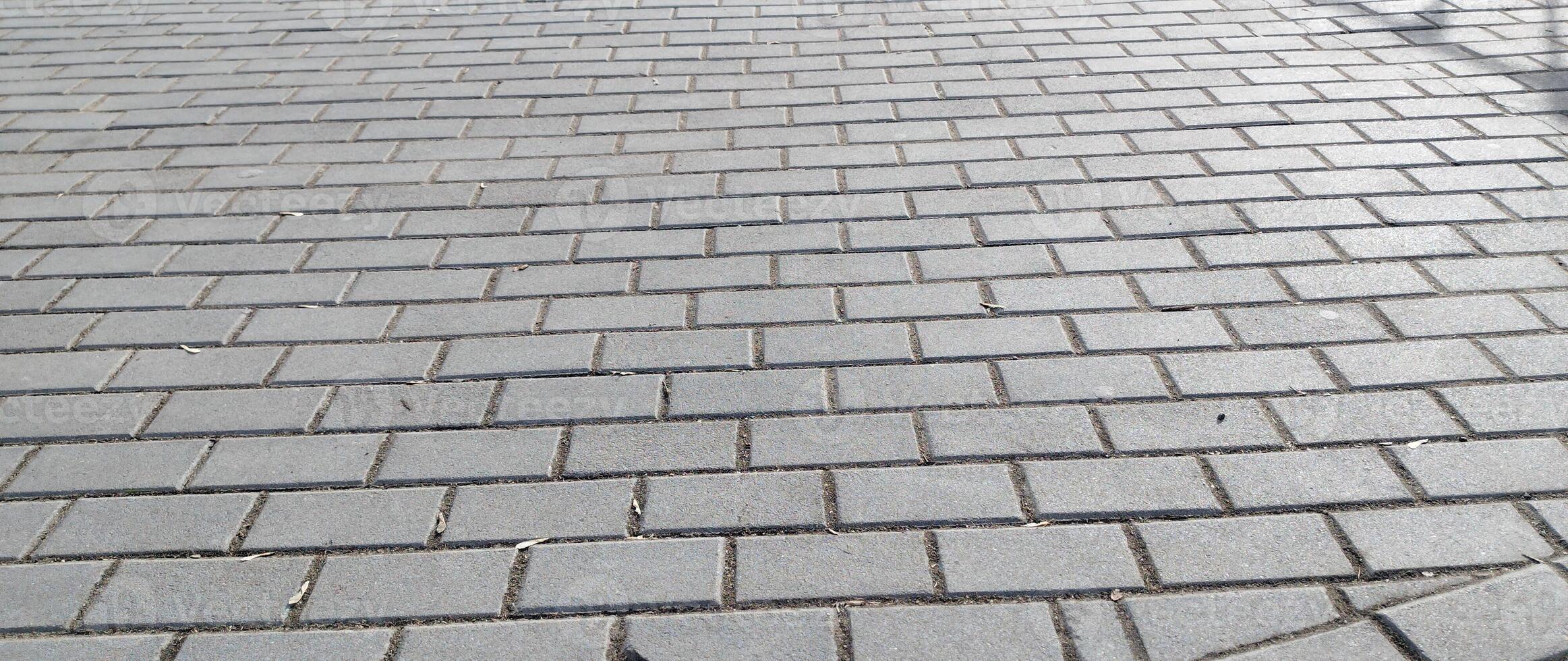 Cobblestone pavement in the city. Nested pavers of Grey colors. Grey brick background. Gray stone tile block background with horizontal texture of gray brick. Gray brick surface. photo