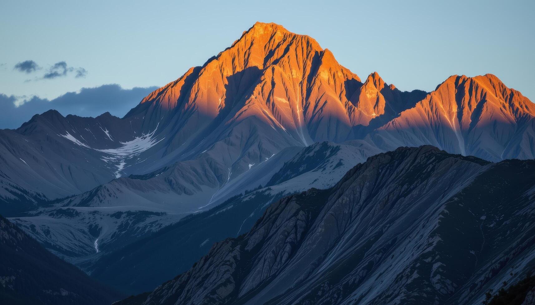 a jagged mountain range illuminated by the first light of day, with shadows cascading down the rocky faces. photo