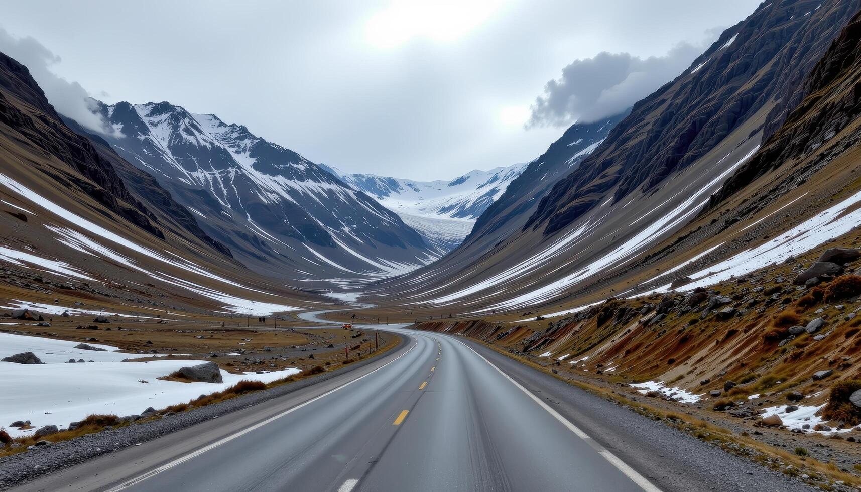 a rocky mountain pass with patches of snow and cloudy skies. photo
