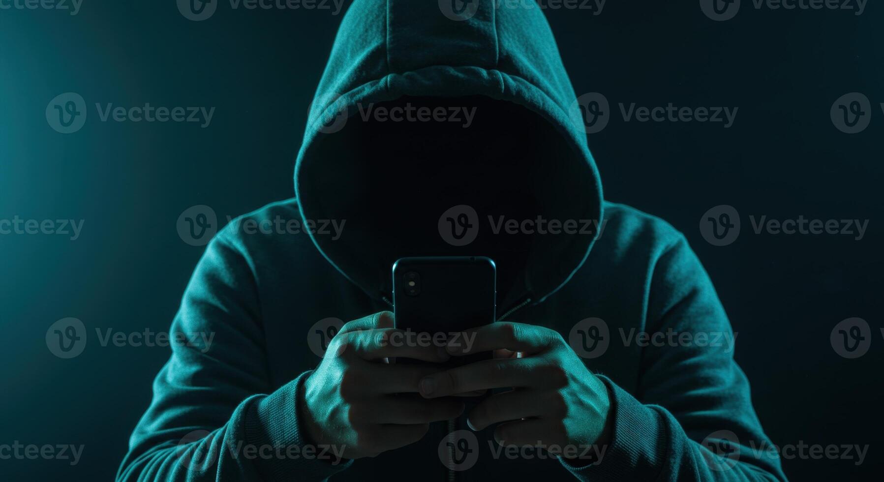 Anonymous hacker in a hoodie using a smartphone, symbolizing cyber security threats and online crime. photo