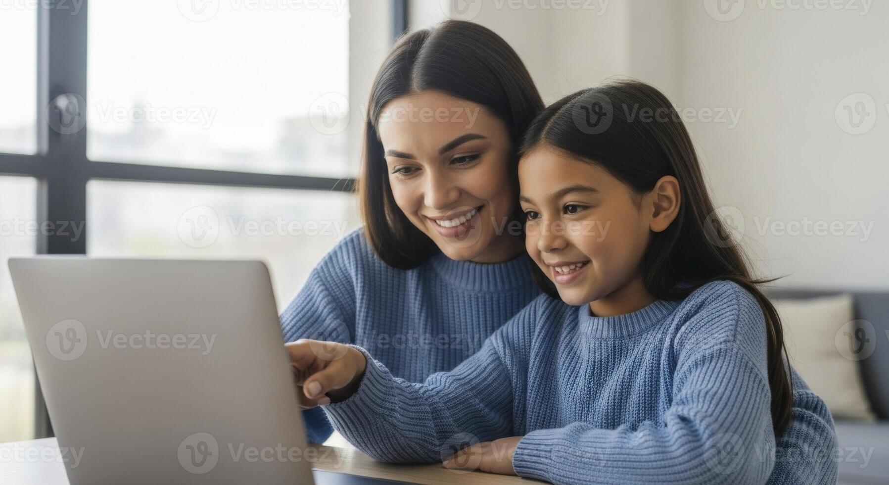 Smiling mother and daughter bonding while looking at a laptop screen together at home. photo