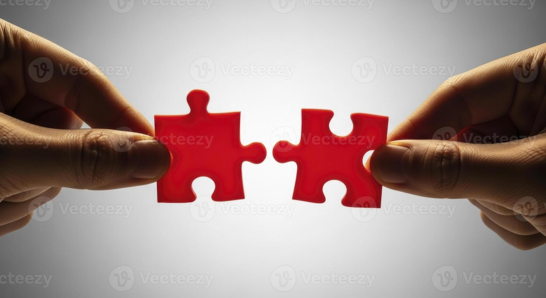 Two hands bringing together vibrant red puzzle pieces, symbolizing connection and problem solving. photo