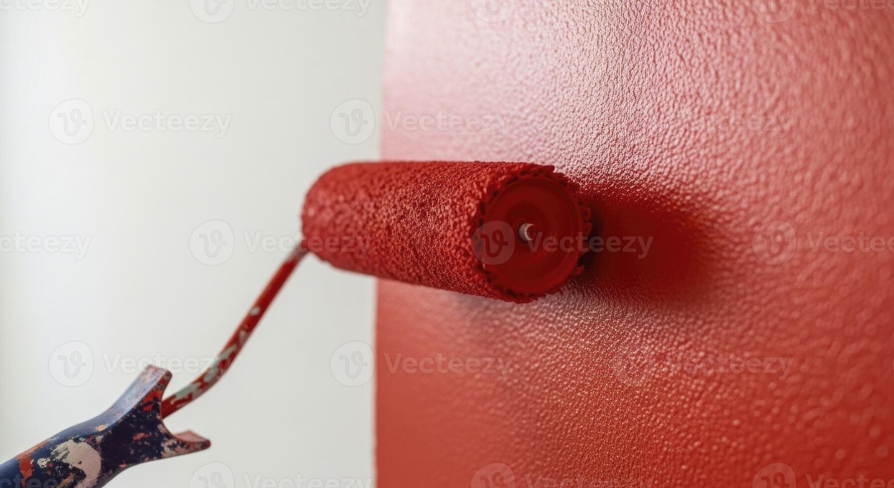 Close up of a paint roller applying vibrant red paint to a textured wall during home renovation photo