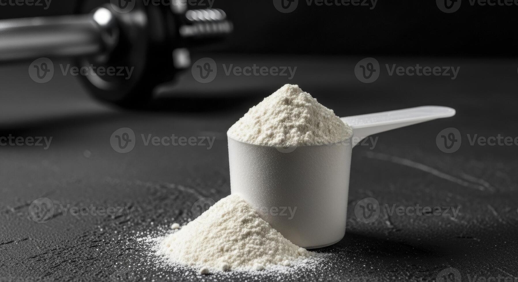 White protein powder in a scoop on a dark surface with a blurred dumbbell. photo