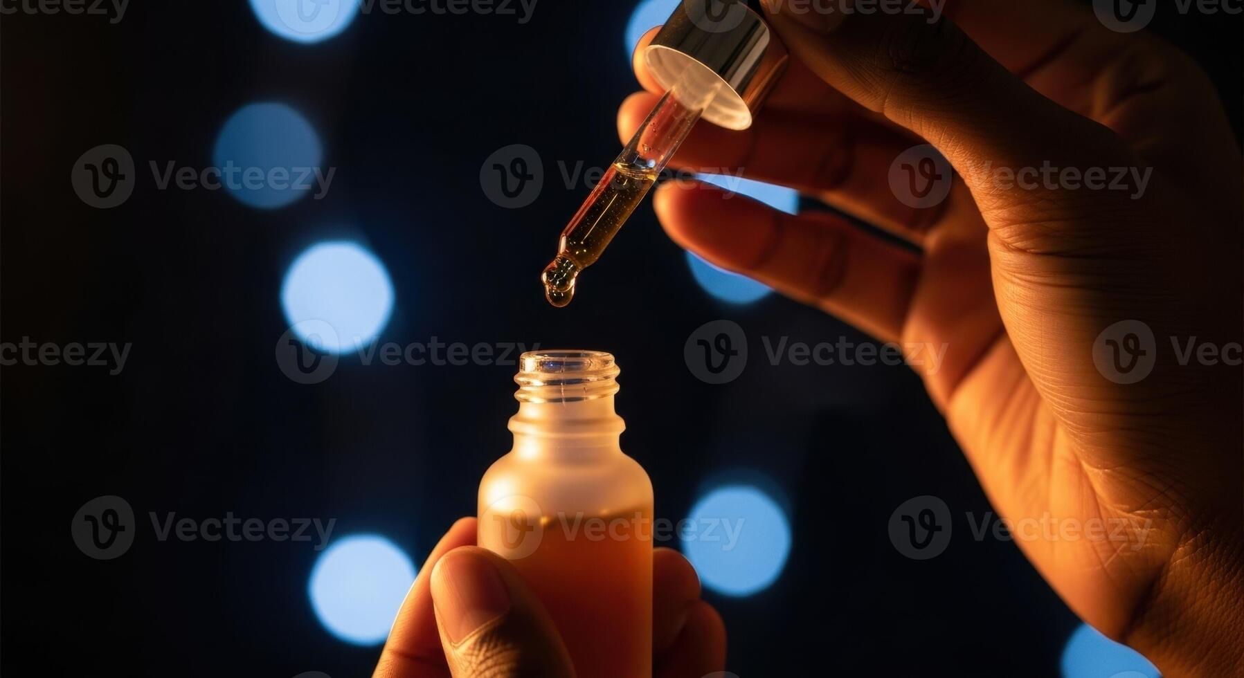 Dark skinned hands holding a frosted glass dropper bottle with amber liquid and falling drop photo