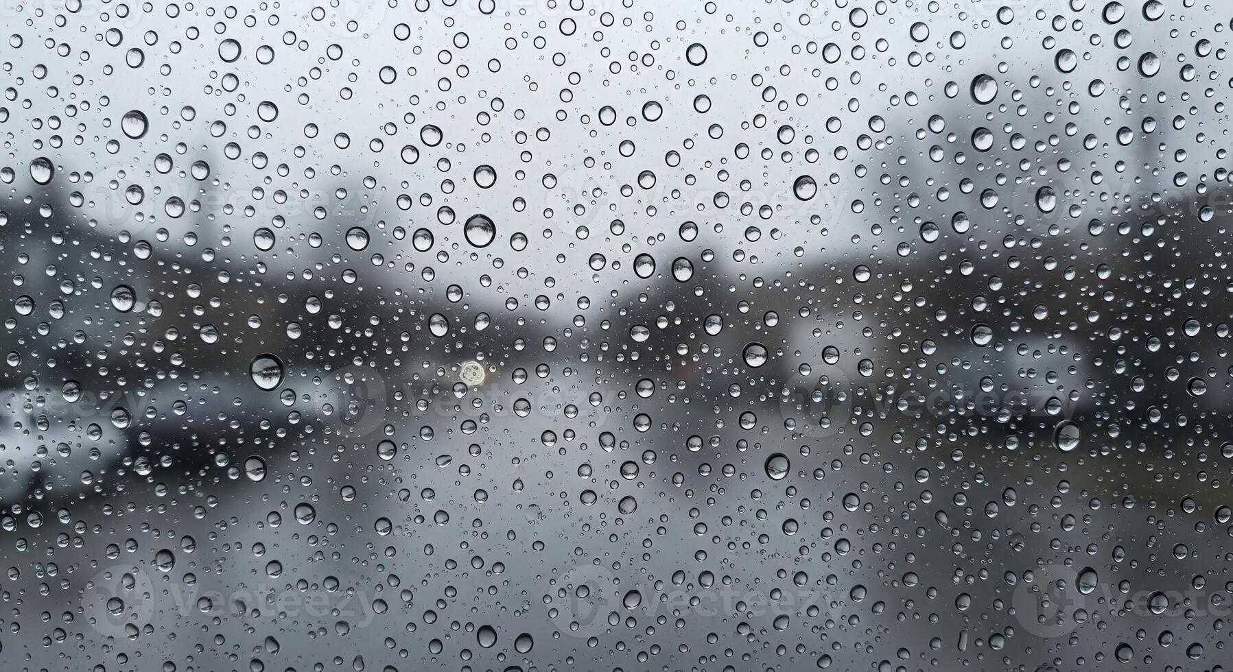 Water Droplets on Glass Surface with Blurred Outdoor Background on a Rainy Day photo