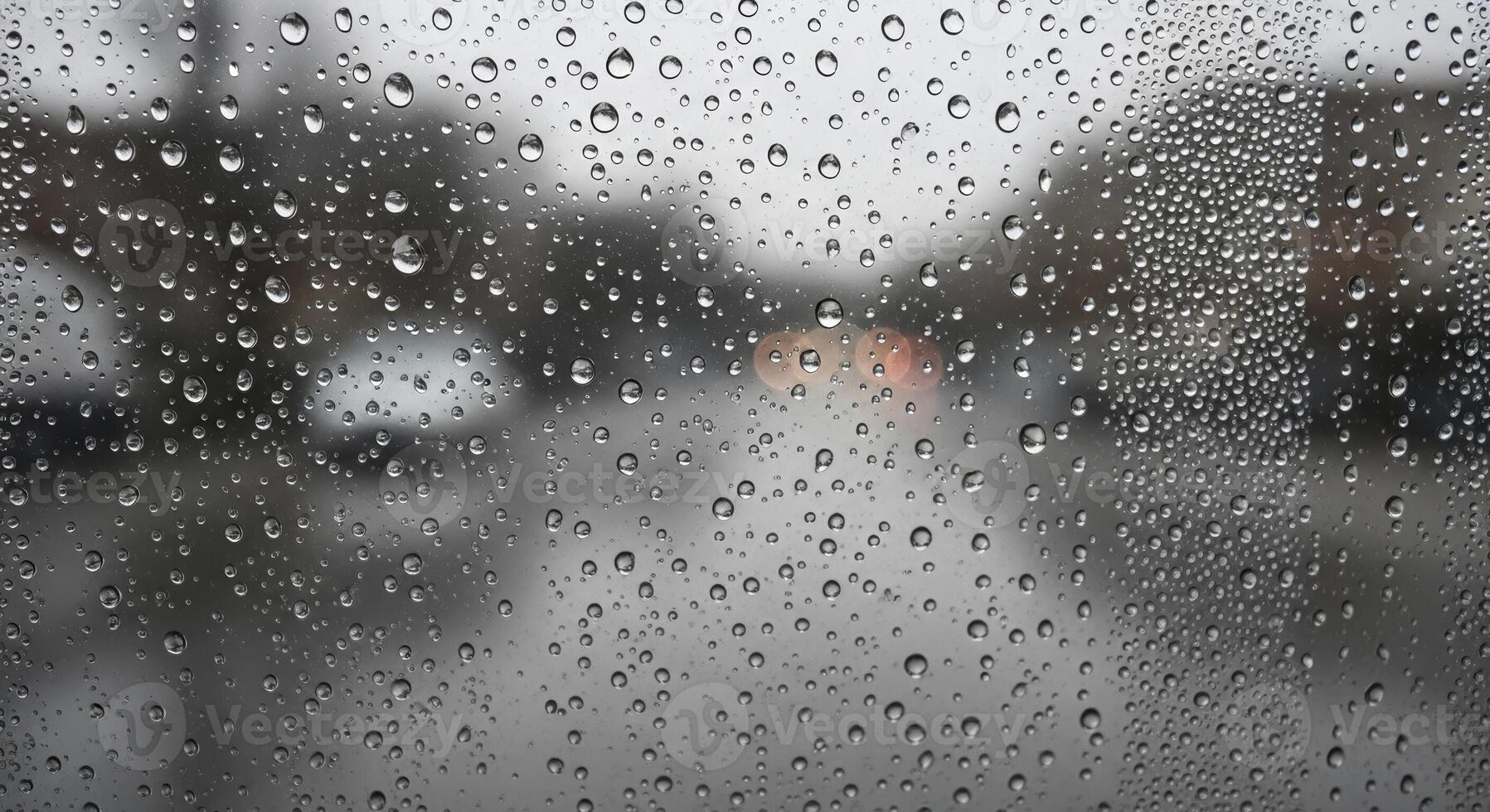 Rain droplets on a glass window with blurred street and vehicles in the background photo