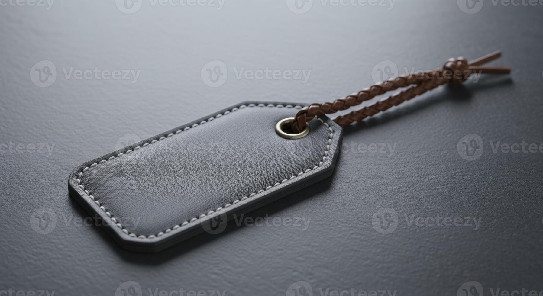 Blank Dark Grey Leather Tag with White Stitching and Braided Strap on a Dark Surface photo