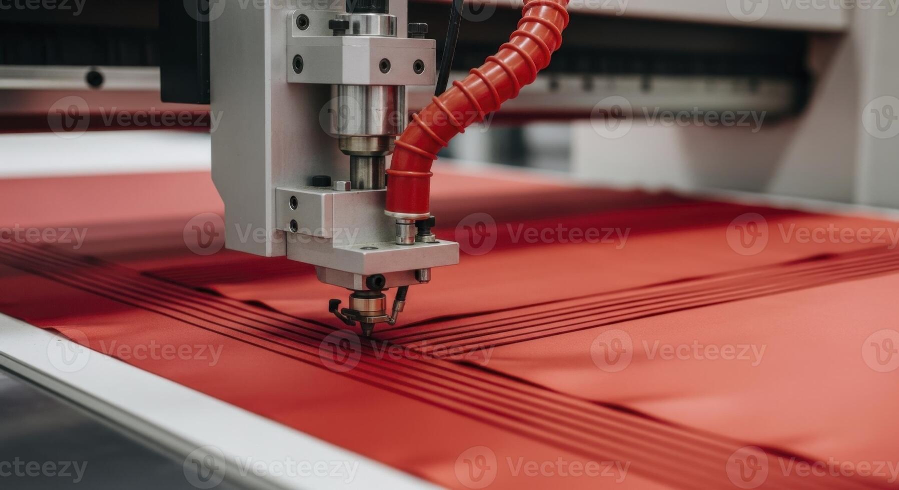 A precision cutting machine working on red material in an industrial manufacturing setting. photo