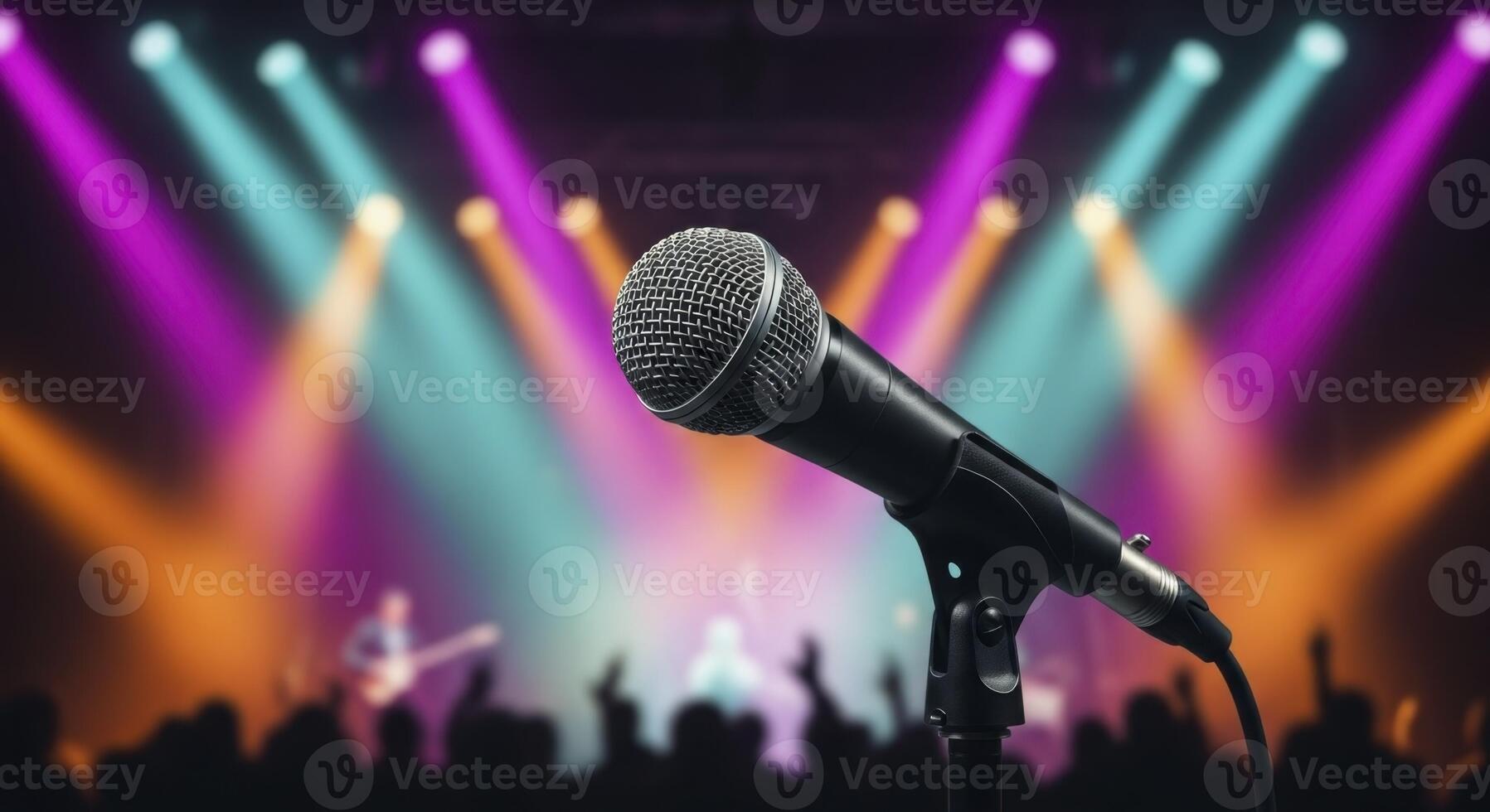 Microphone on stage with colorful spotlights and blurred audience at a live concert photo