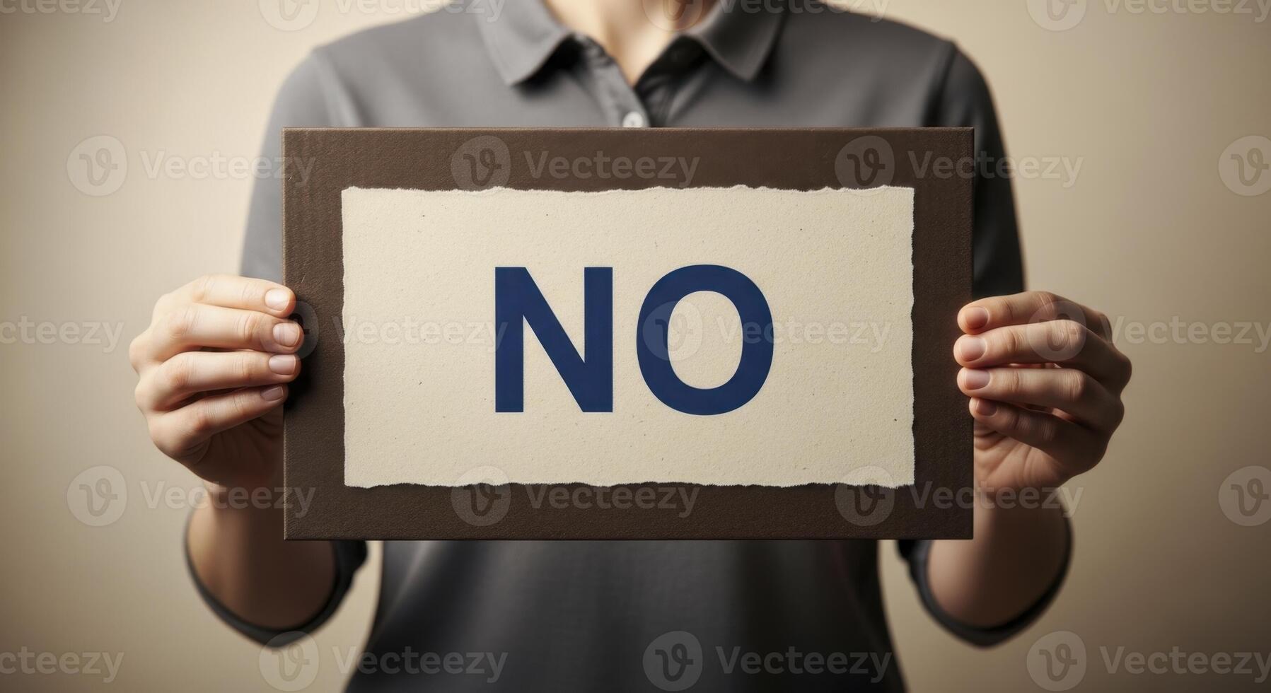 Individual holding a framed sign displaying the word NO, symbolizing refusal and rejection photo