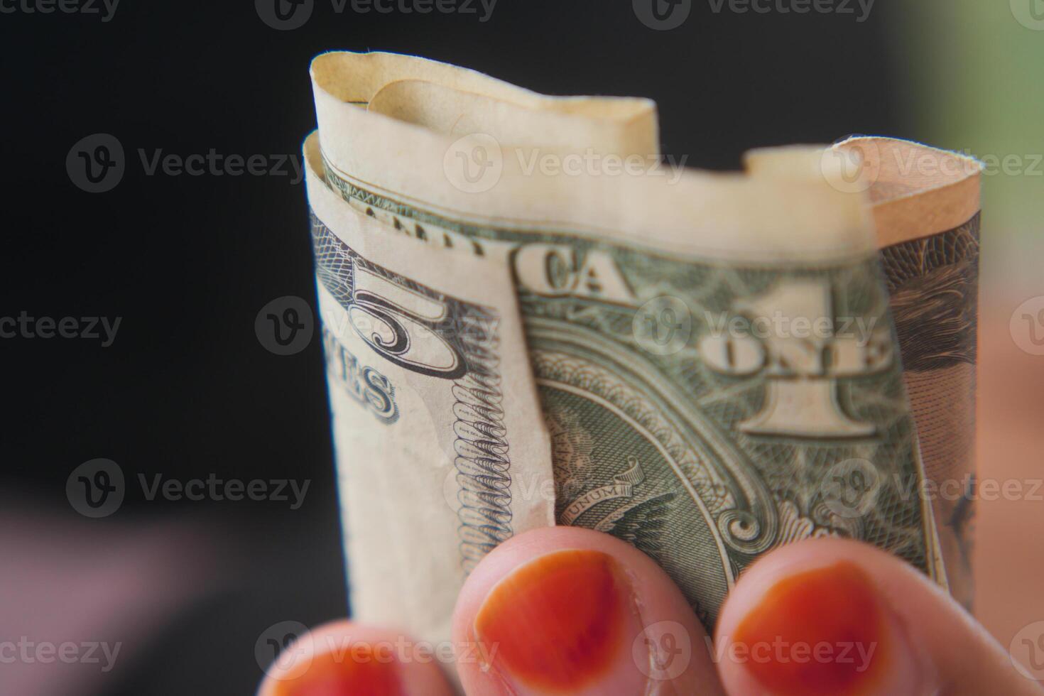 Holding cash in hand with vibrant orange nails photo