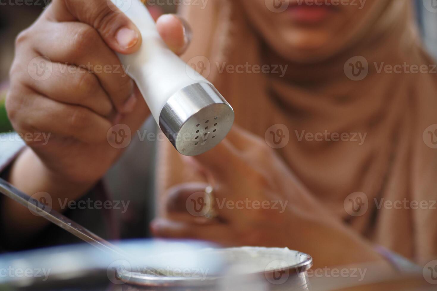 Woman seasoning food with salt at a casual dining setting photo