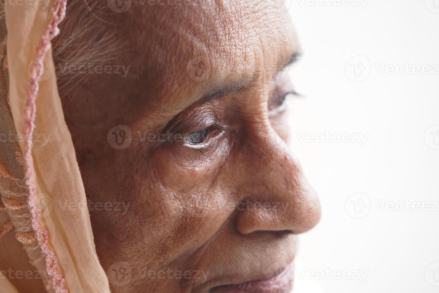 Elderly woman gazing thoughtfully near window light photo