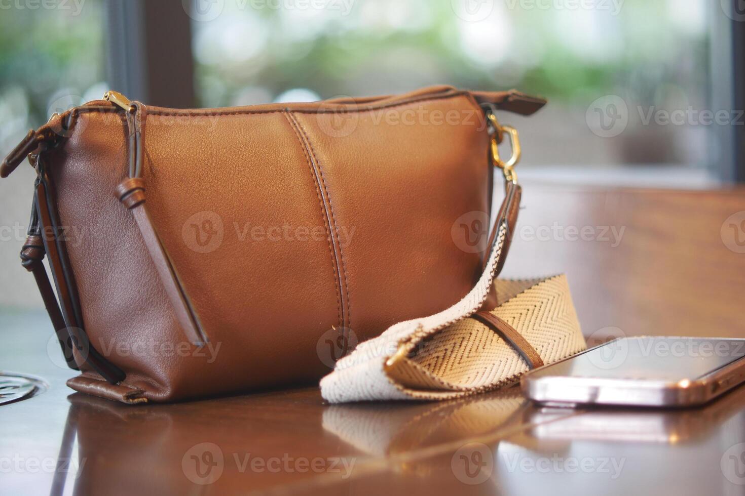 Brown leather handbag and smartphone on a table photo