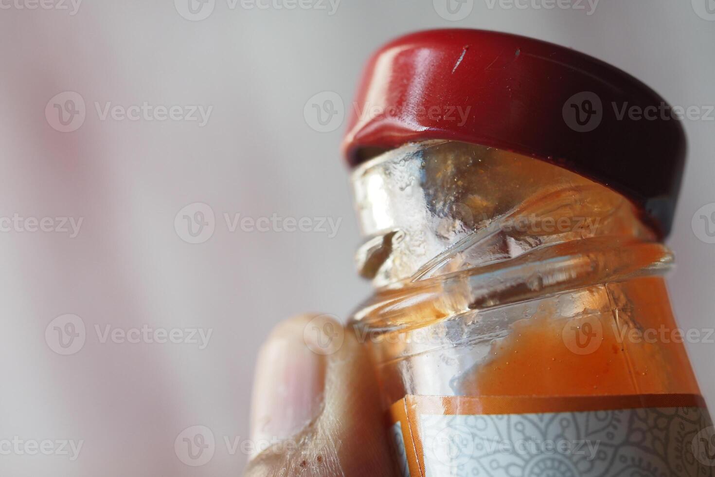 Close up of a glass bottle with a red cap held in hand photo