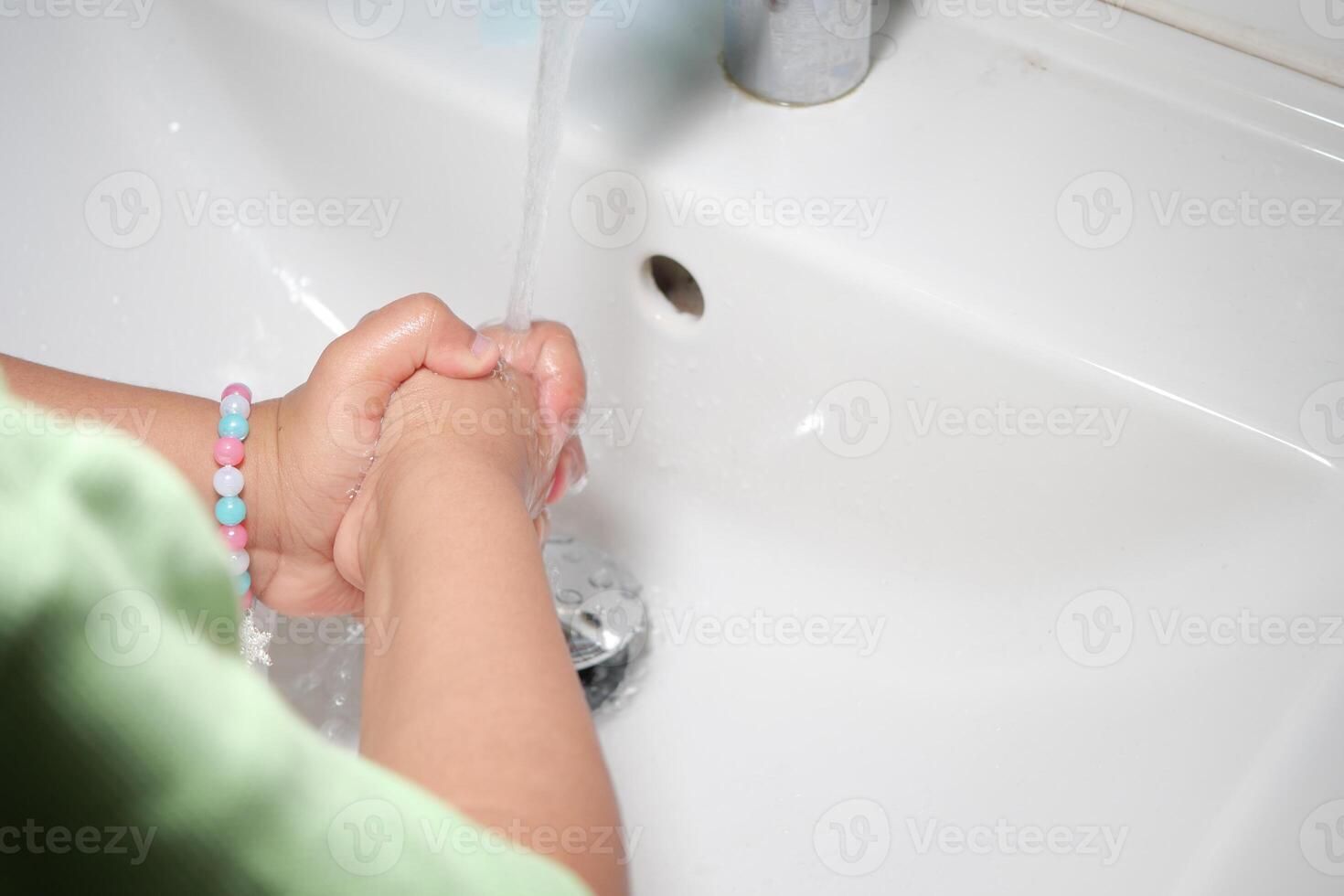 Child washing hands at a sink in a bathroom photo