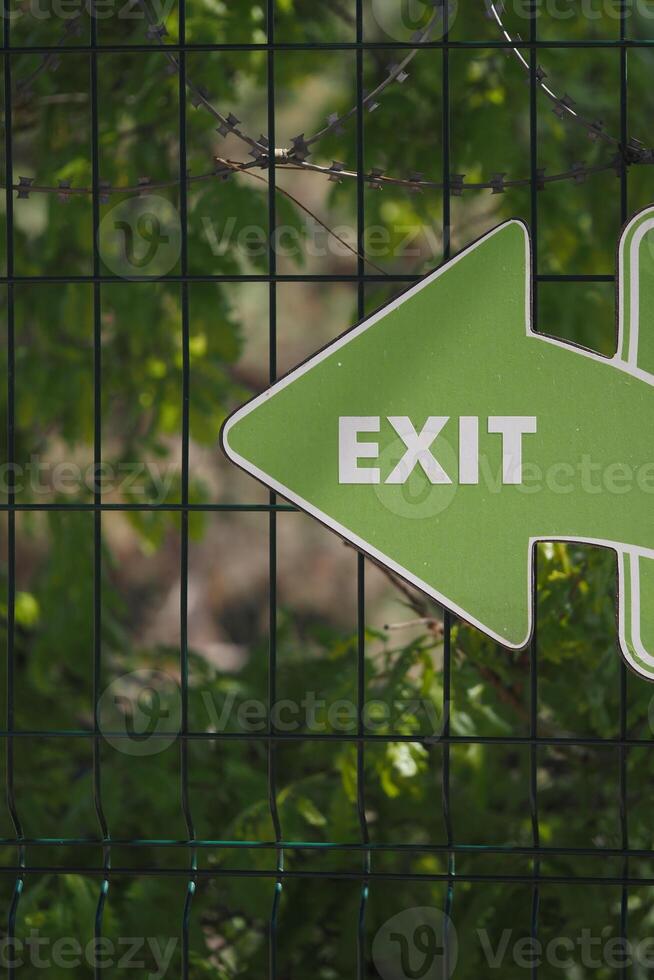Green exit sign pointing left in nature setting photo
