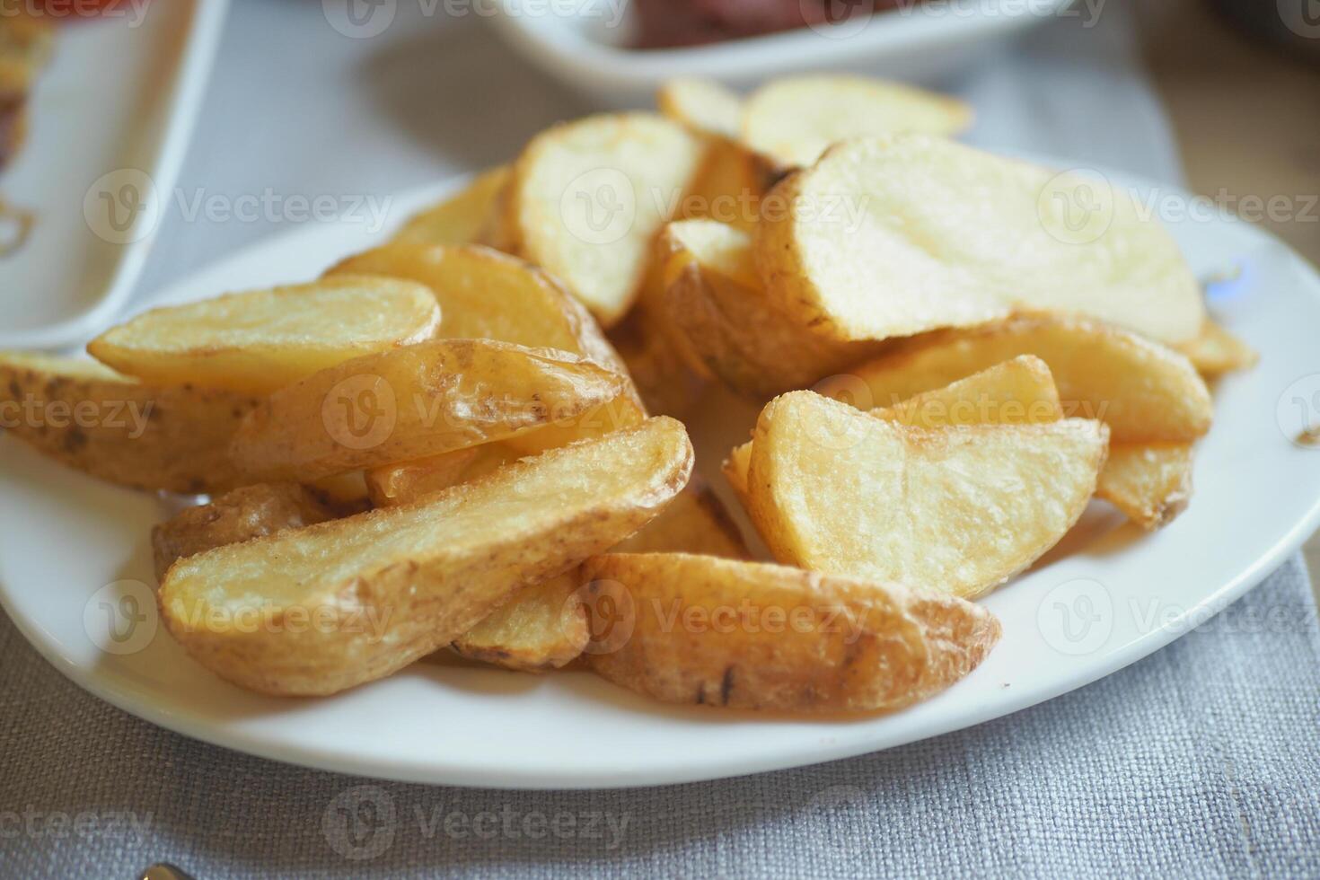 Crispy golden potato wedges served on a white plate photo
