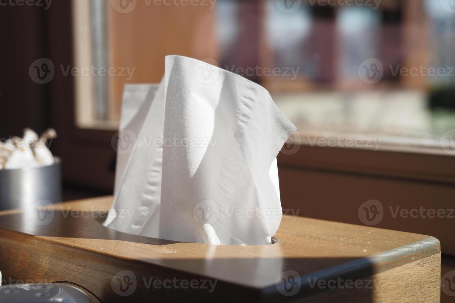 Tissue box on wooden table with sunlight streaming in photo