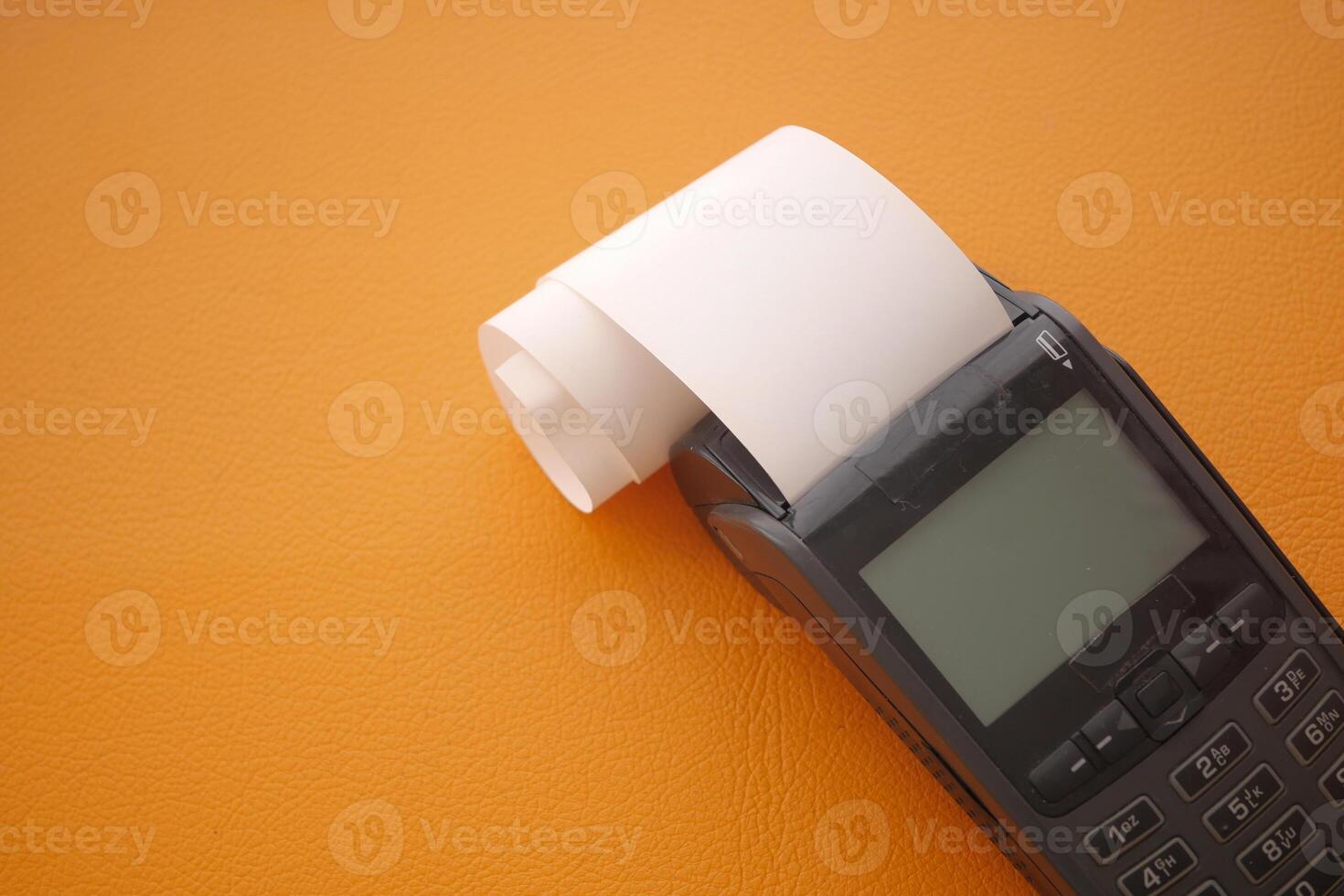 Old thermal printer on orange background with paper roll photo