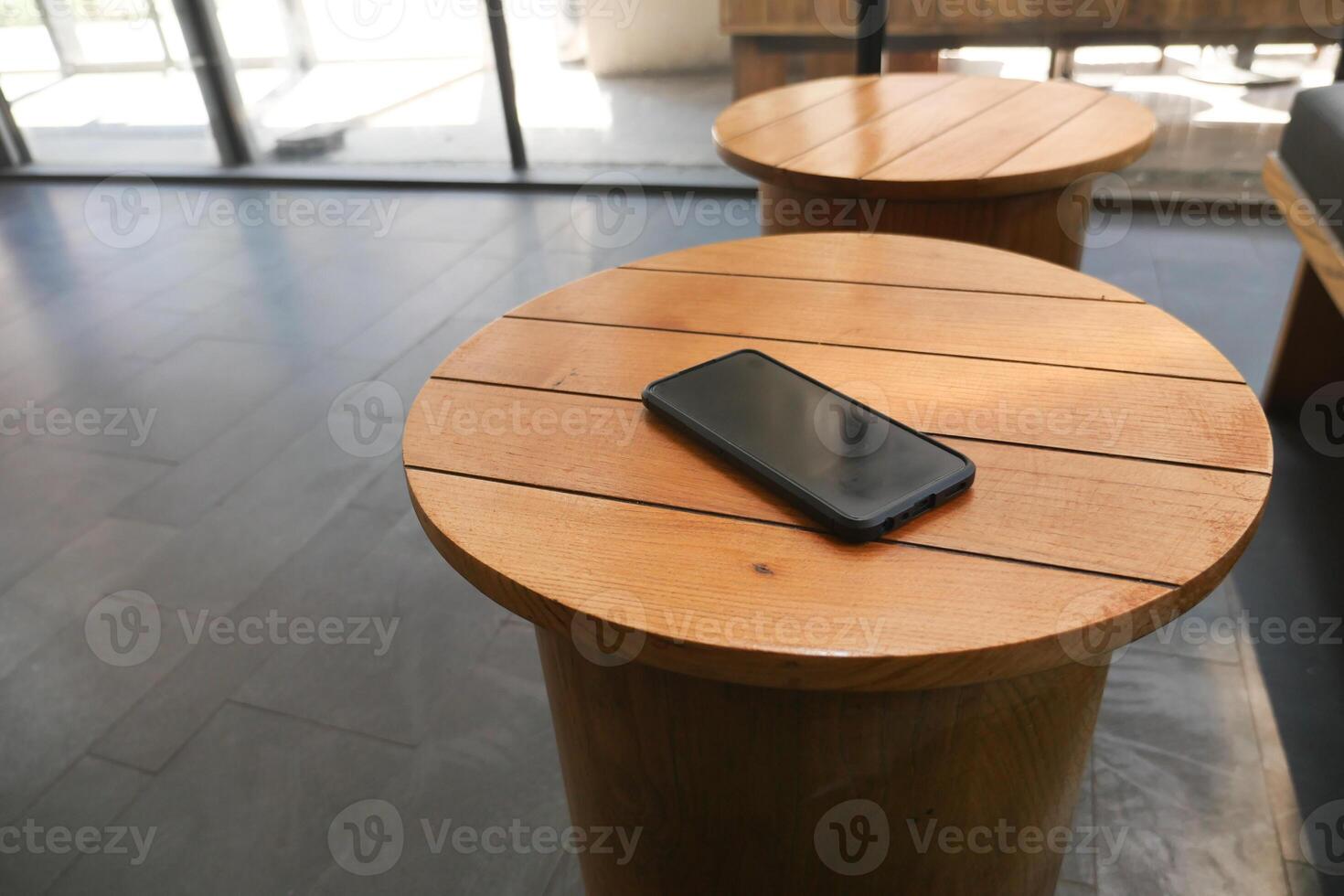 Phone resting on wooden table in modern lounge area. lost smart phone concept photo
