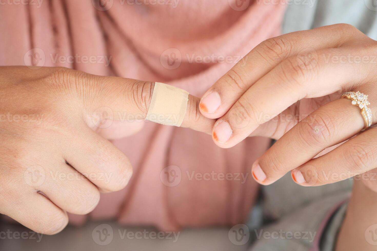 Hands applying a bandage on a finger at home photo