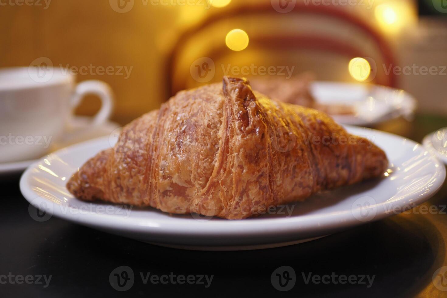 Freshly baked croissant on a plate with warm lighting photo