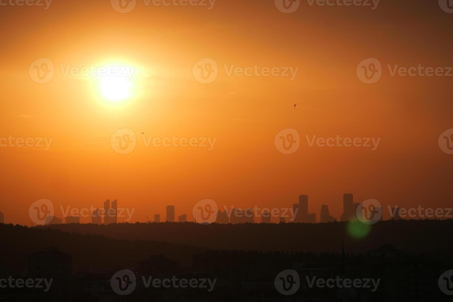 Sunset over city skyline with silhouettes of buildings photo