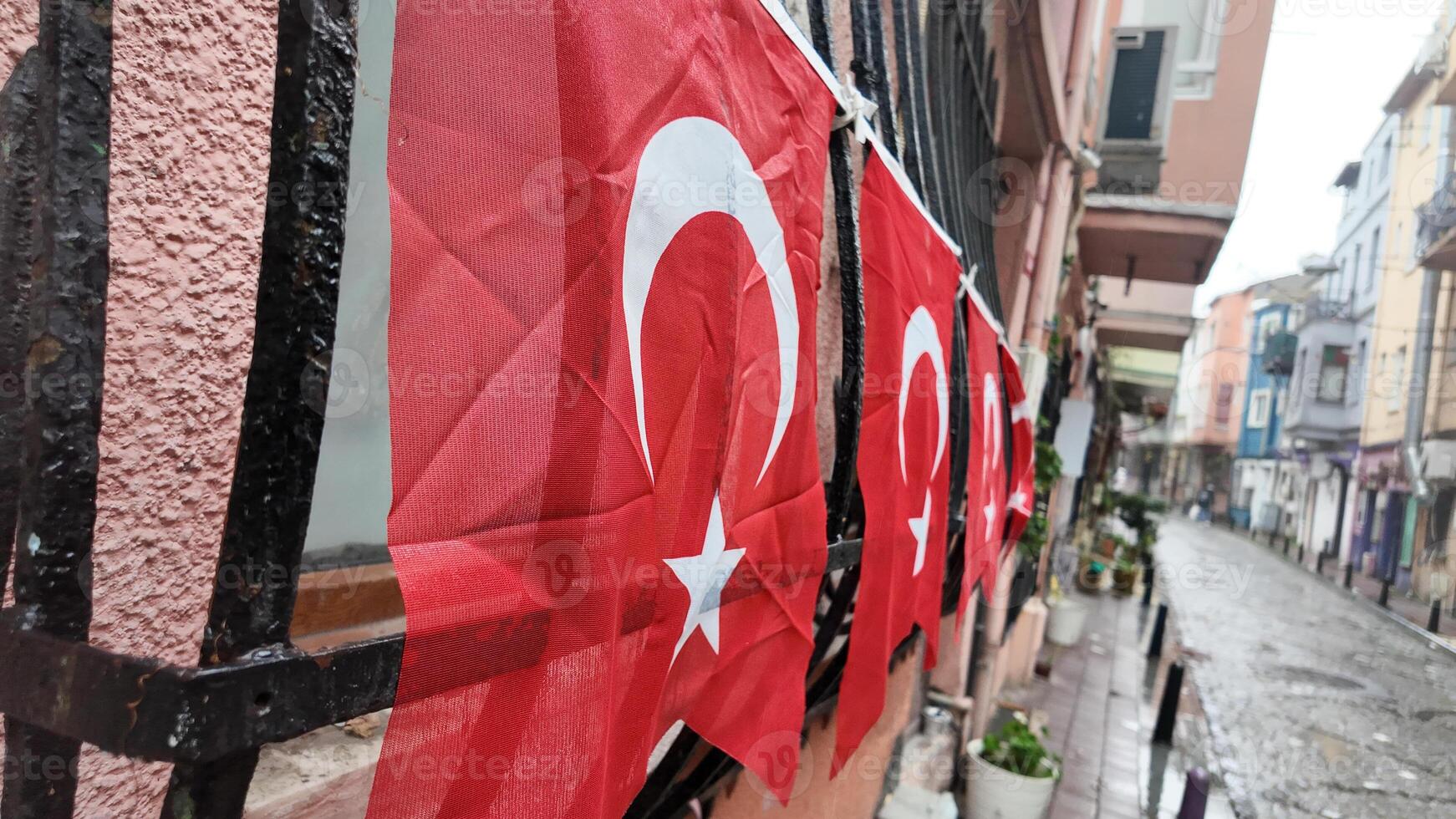 Turkish flags displayed along a rainy street in a city photo