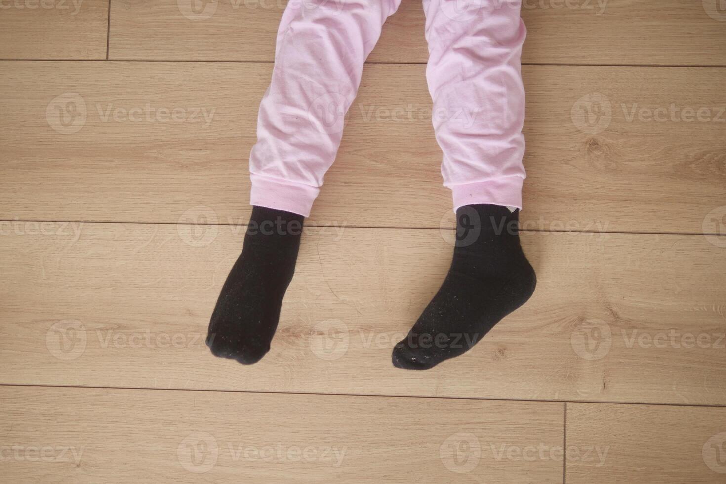 Child in pink pajamas and black socks on floor photo