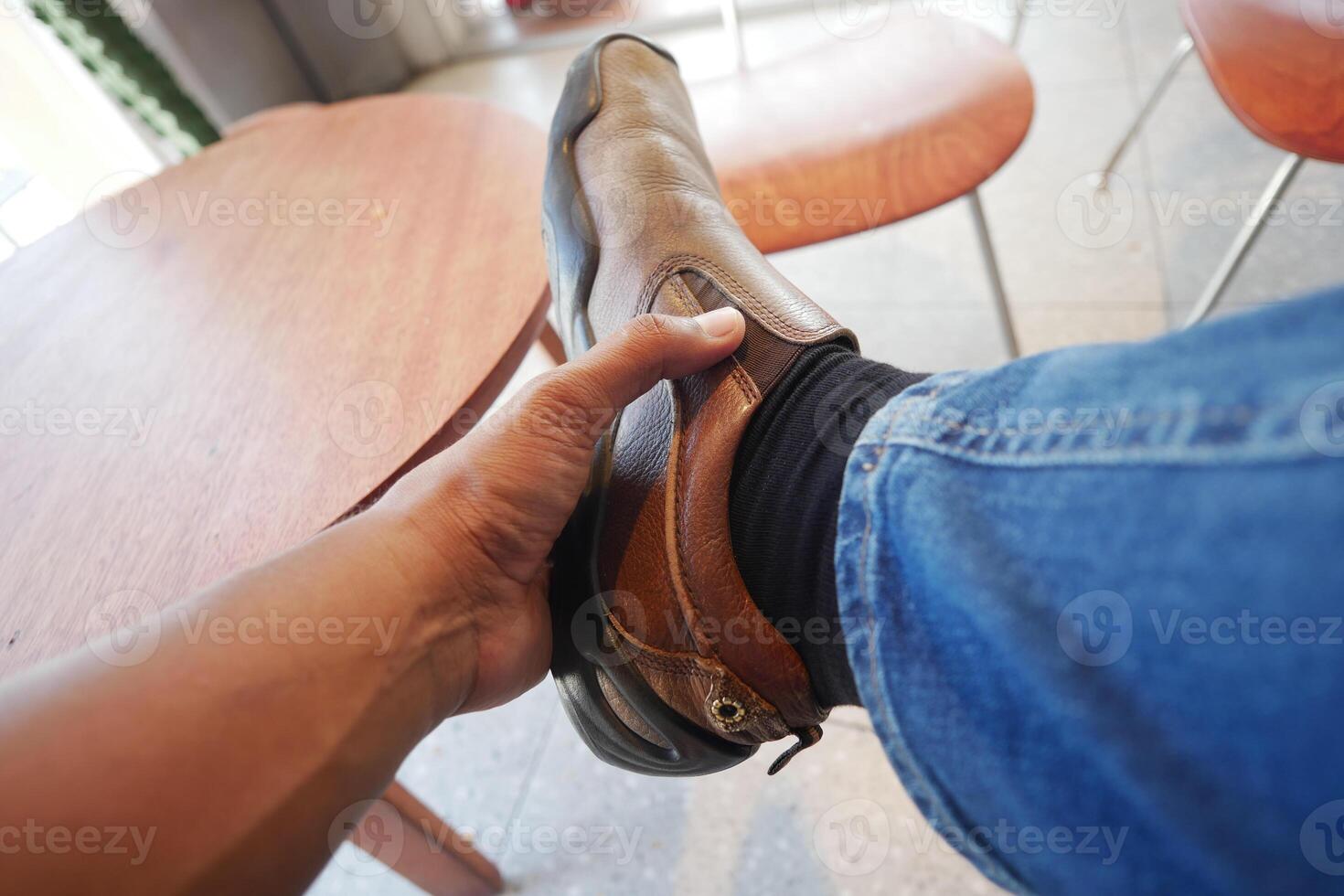 Adjusting footwear while seated at a wooden table photo