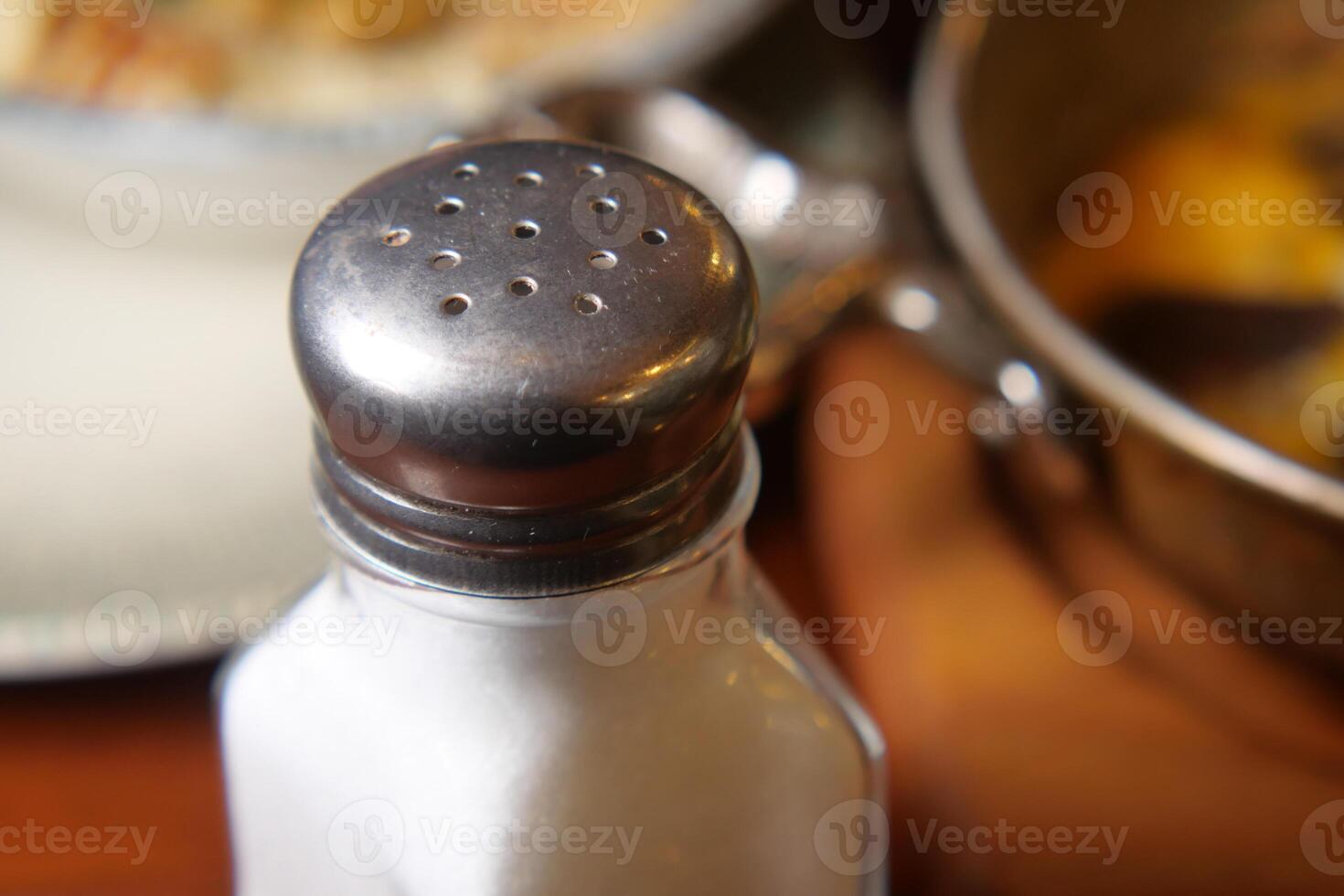 Salt shaker placed beside a delicious meal on a table photo