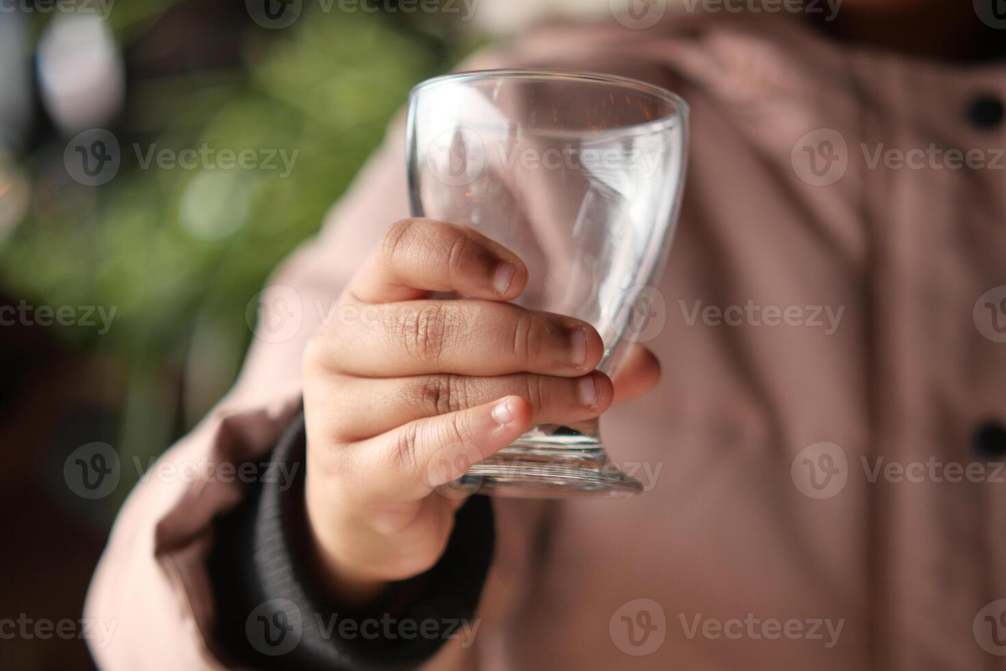 Child holding a clear glass cup in cozy setting photo