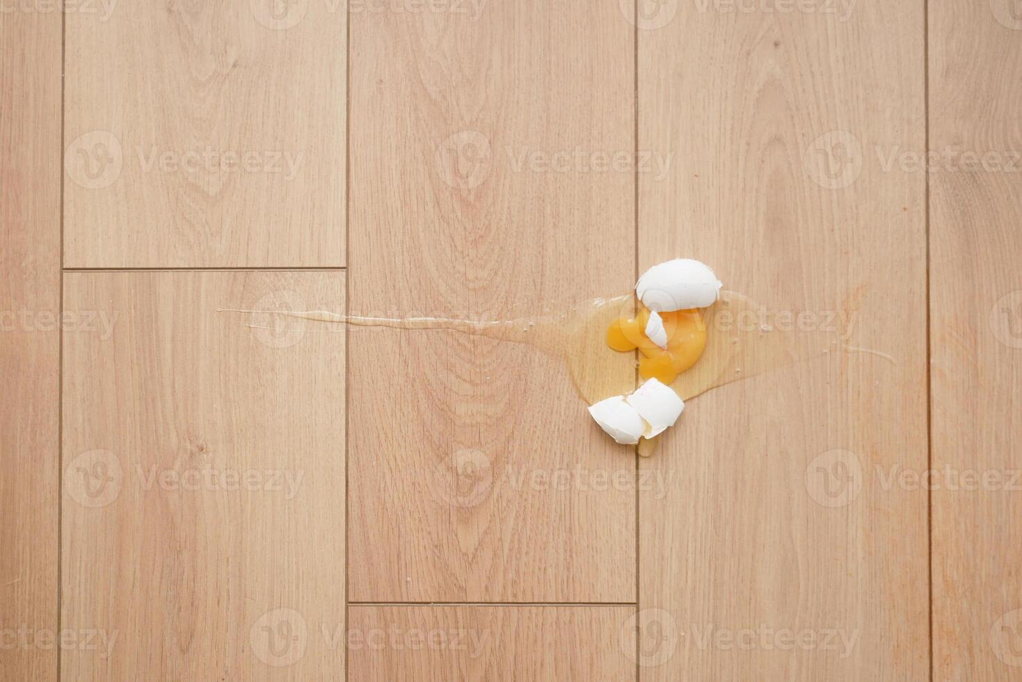 Eggshells and yolk spill on wooden floor photo