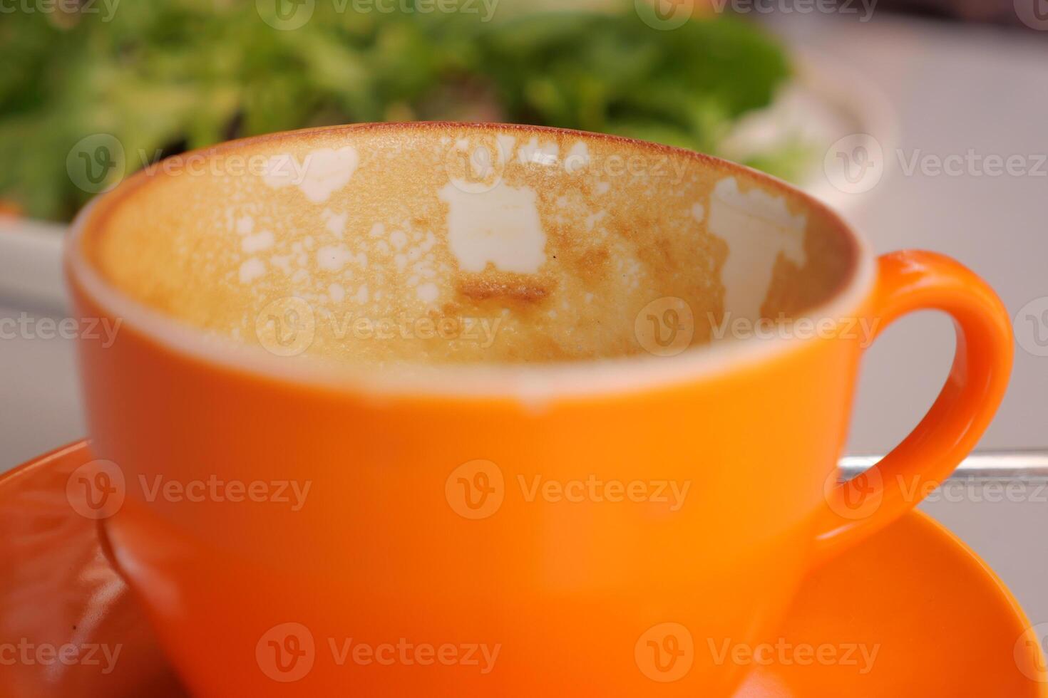 Empty orange coffee cup with remnants at cafe table photo