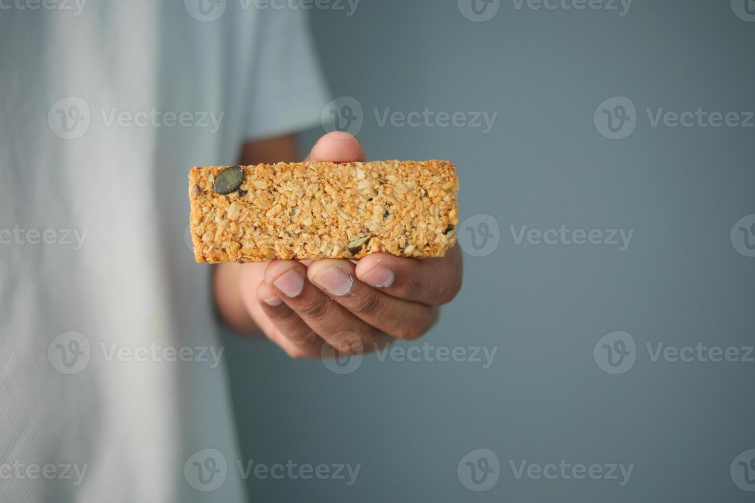 Healthy snack bar held in hand against a simple background photo
