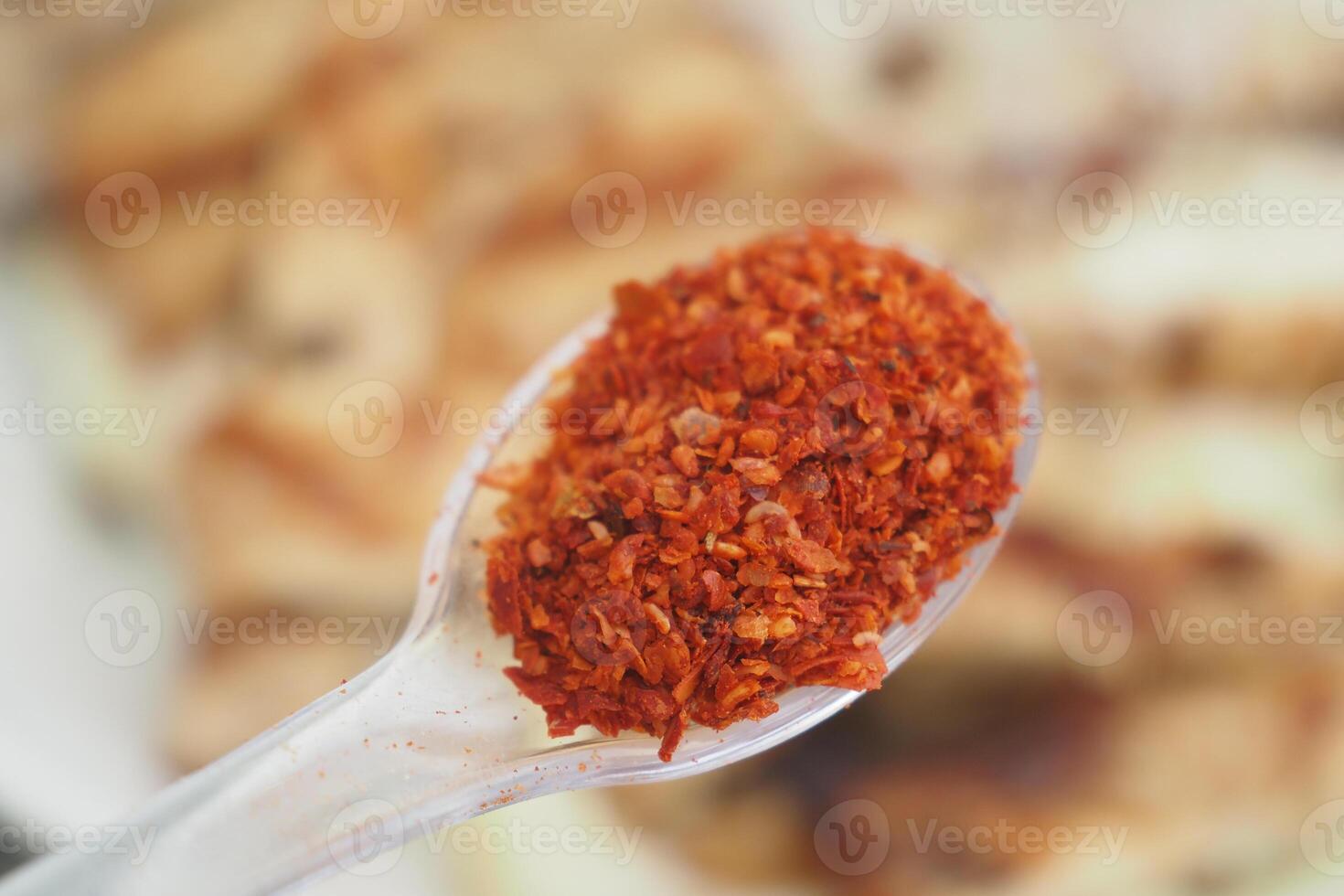Spicy red chili flakes in a spoon ready for seasoning photo