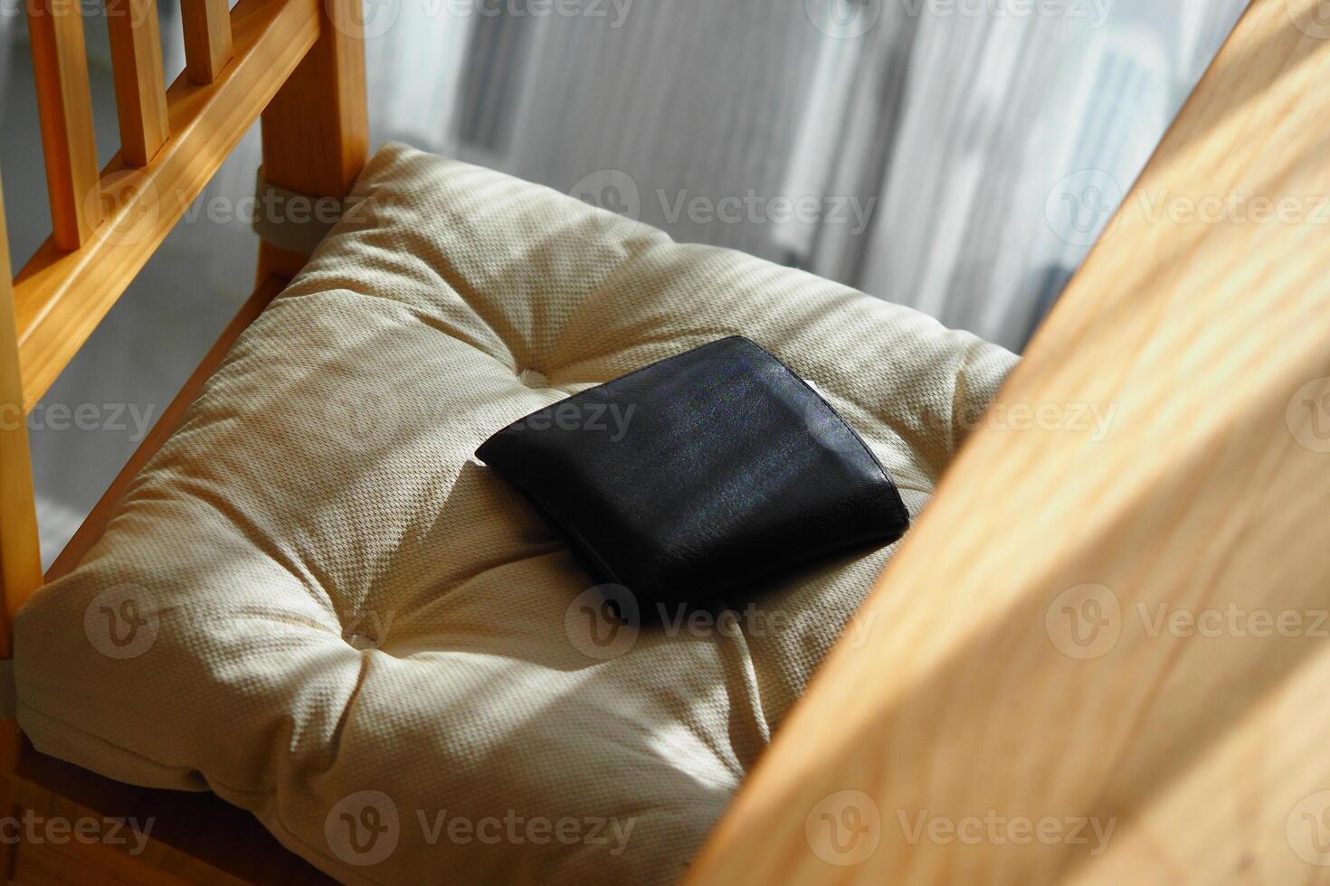 Black wallet resting on a fabric cushion in a cozy setting. lost wallet concept photo