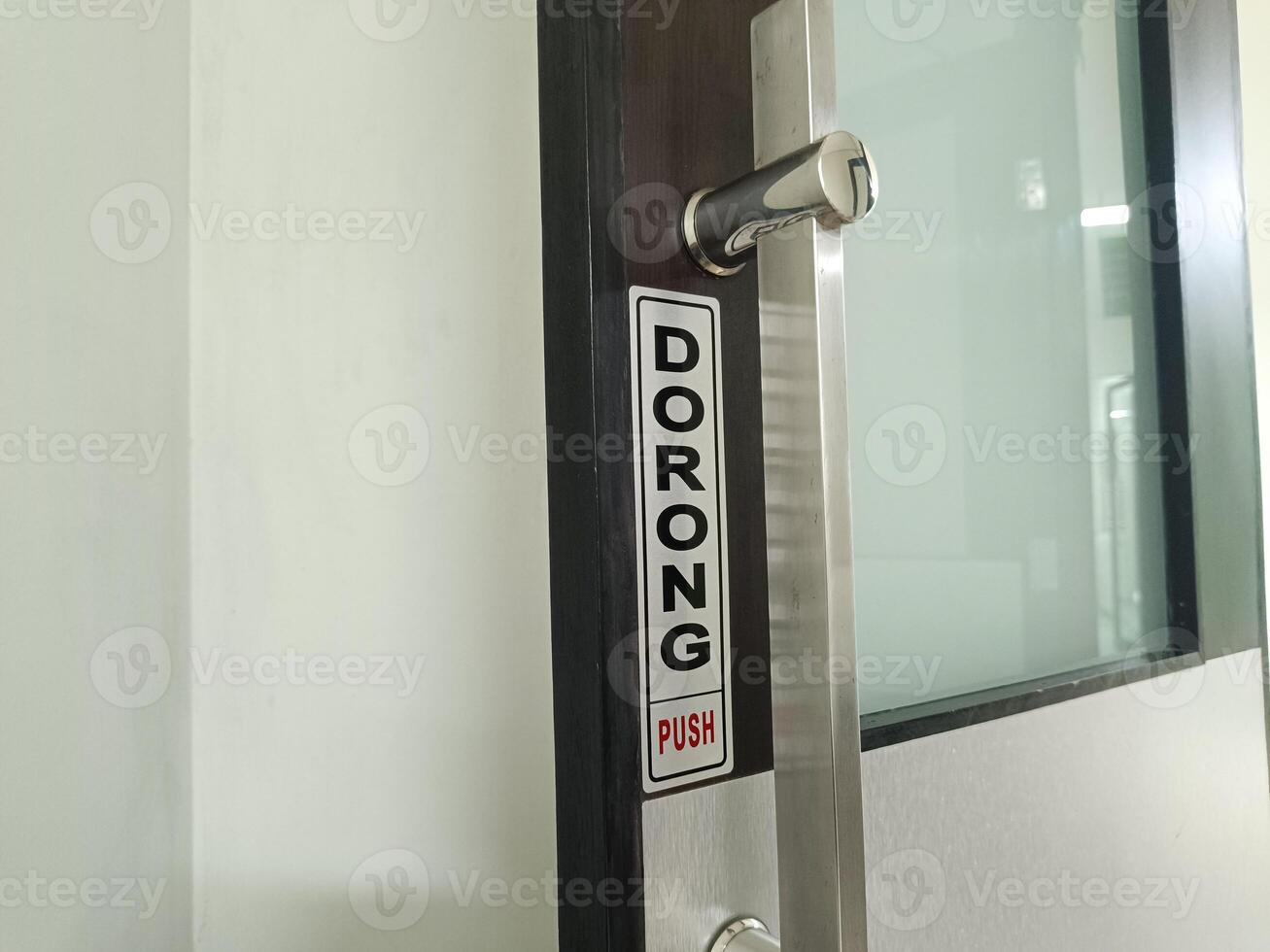 A sign indicating that the door must be pushed to open. Door handle. PUSH. photo