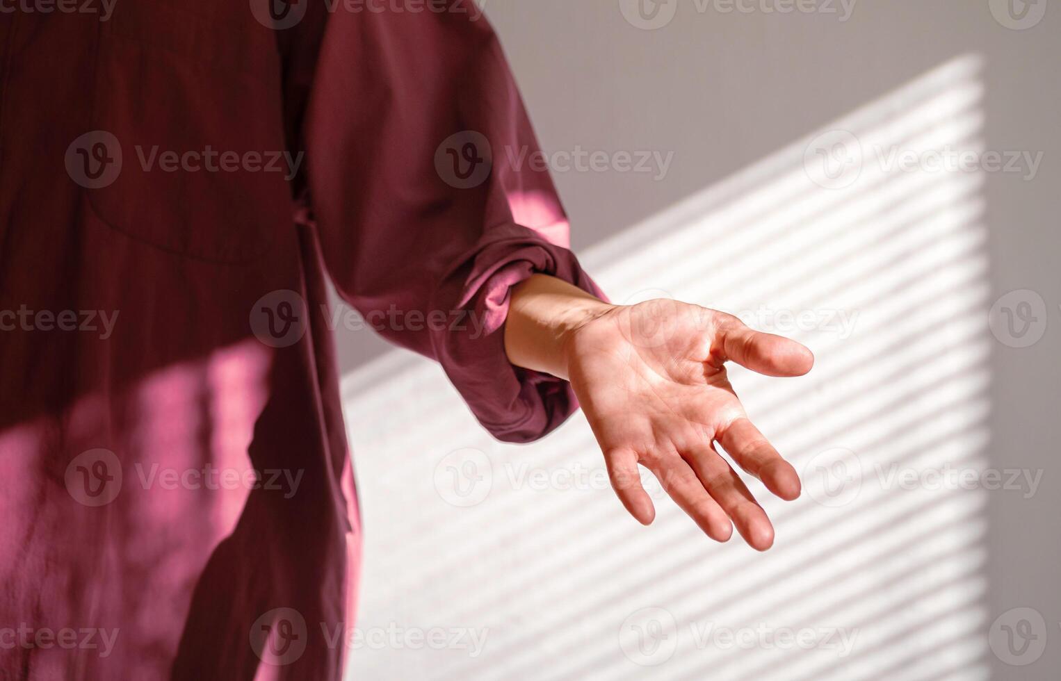 Person Reaching Out Hand in Dappled Shadow of Window Blind on Wall. Offer Help or Assistance. Trust Concept. photo