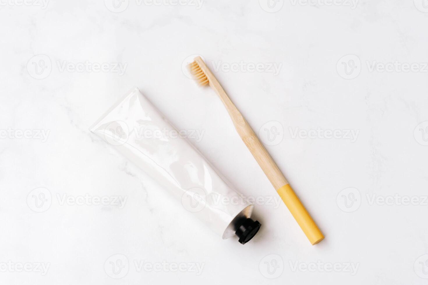 Top view of white metal tube without label and toothbrush on white background photo