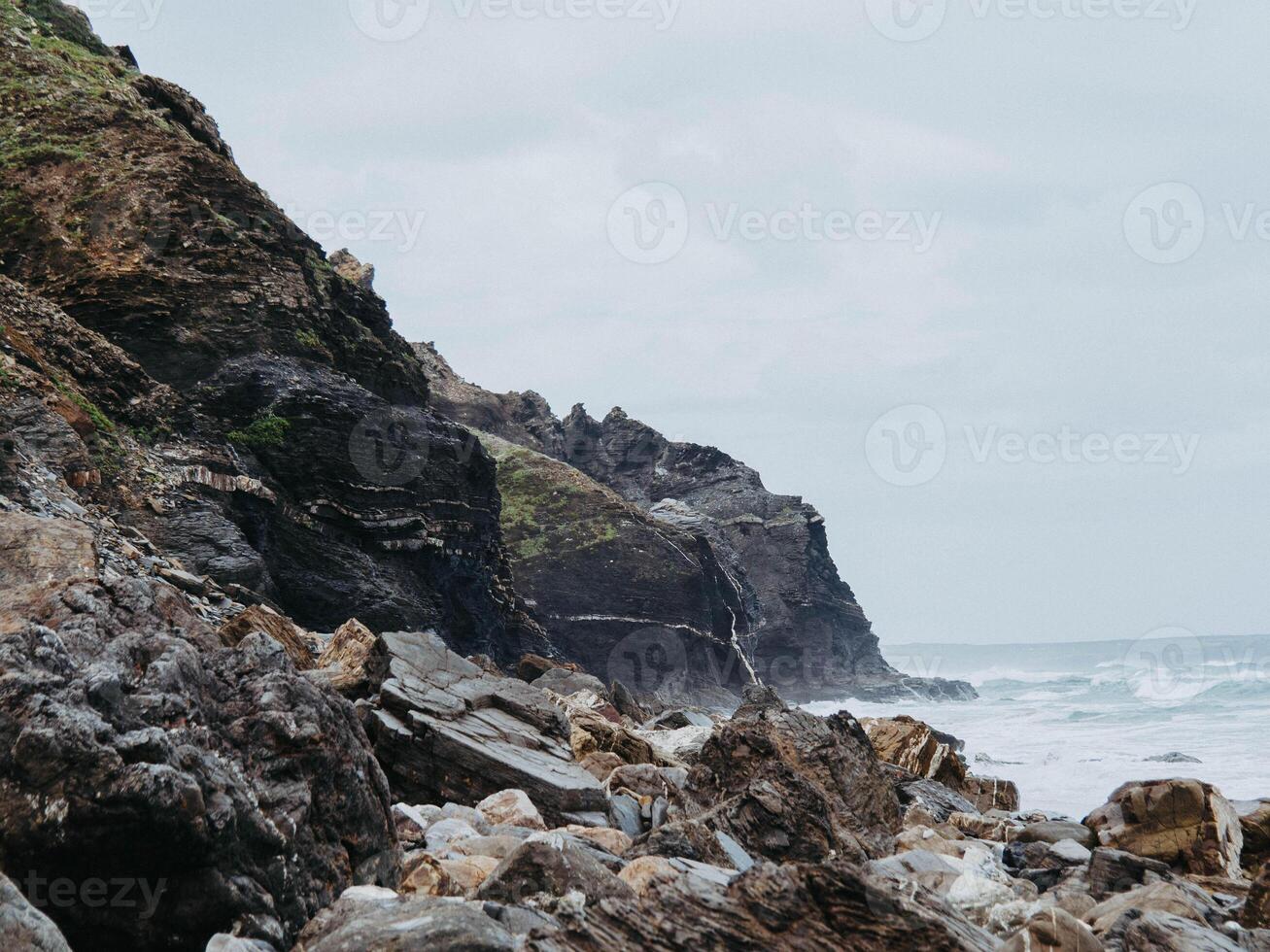Beautiful view of a wild stone beach and oceanic waves with splashes hitting the shore photo