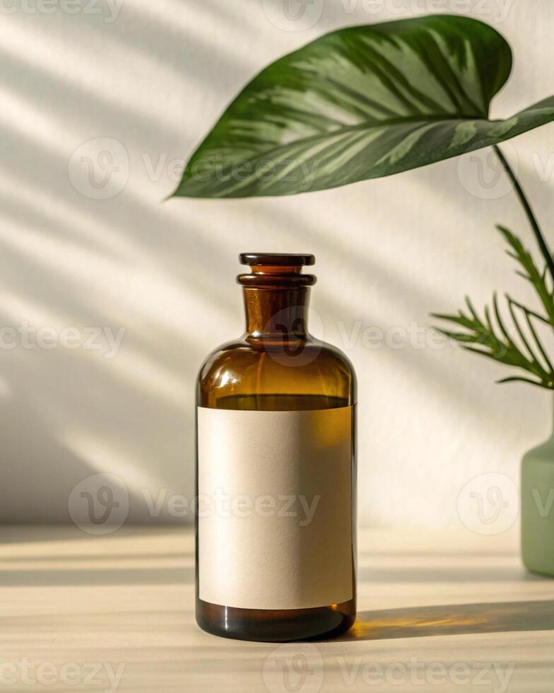 A bottle of essential oil is on a wooden table with a plant in the background photo