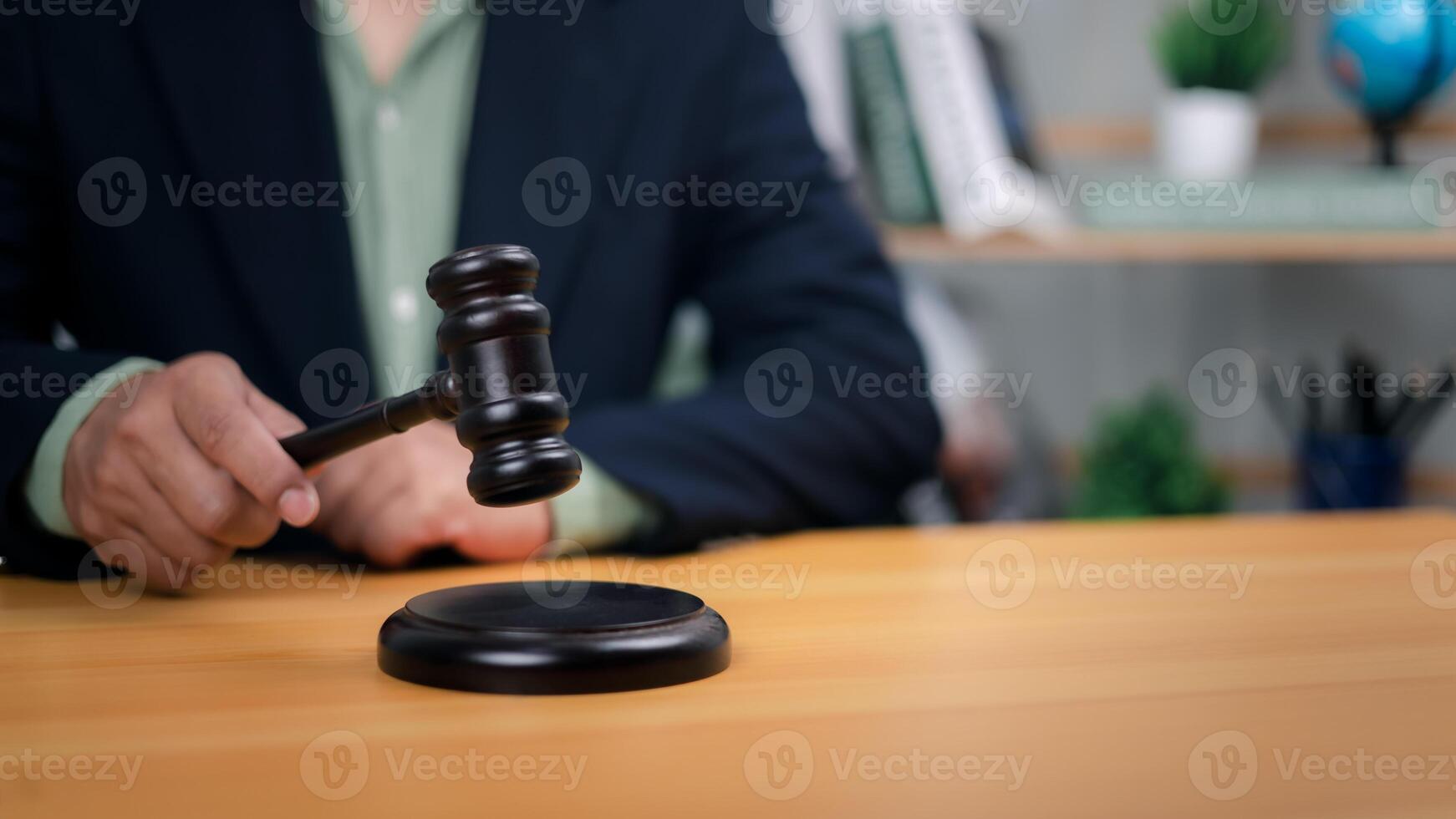 Hand holding gavel poised above base. Symbolizes justice, legal authority, and decisive action in court, law, or auctions. Ideal for representing judgment, powerful decisions, dispute resolution now. photo