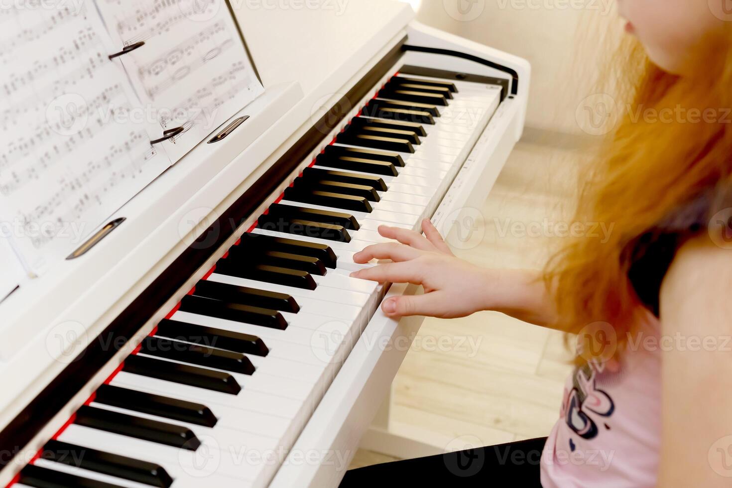 kid girl sits at the piano playing a melody photo