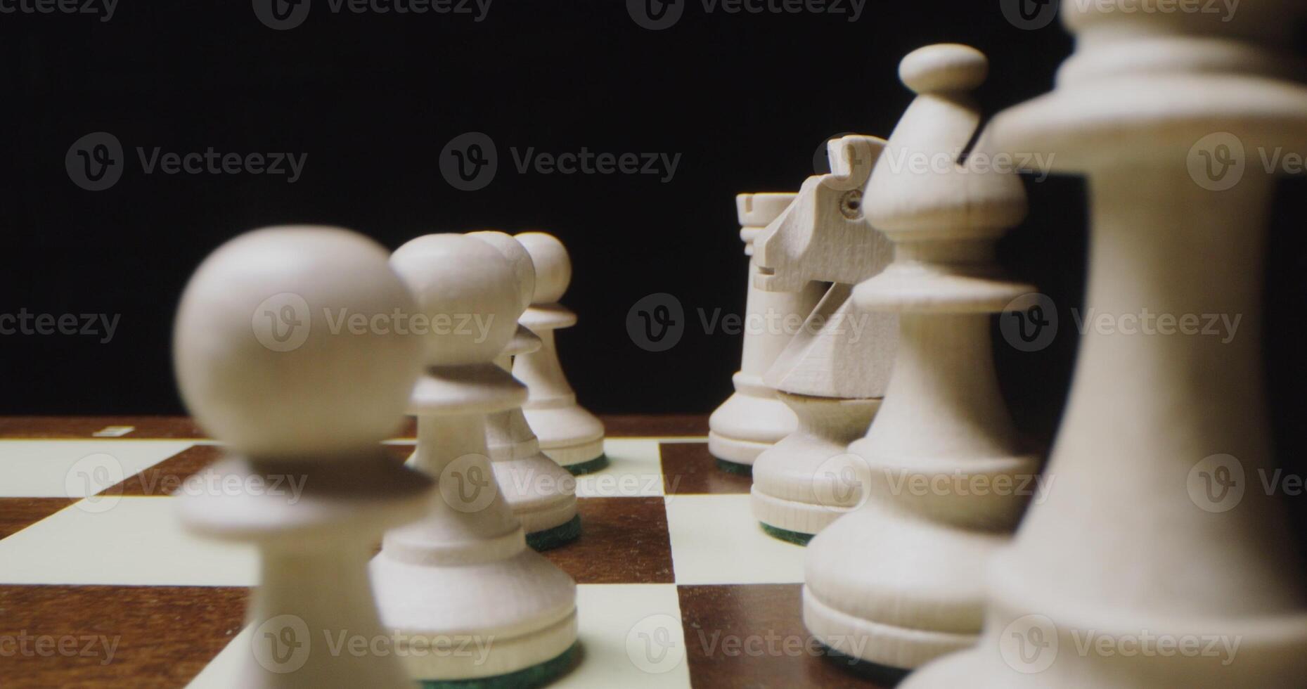 White chess pieces are lined up in even rows on a game board photo
