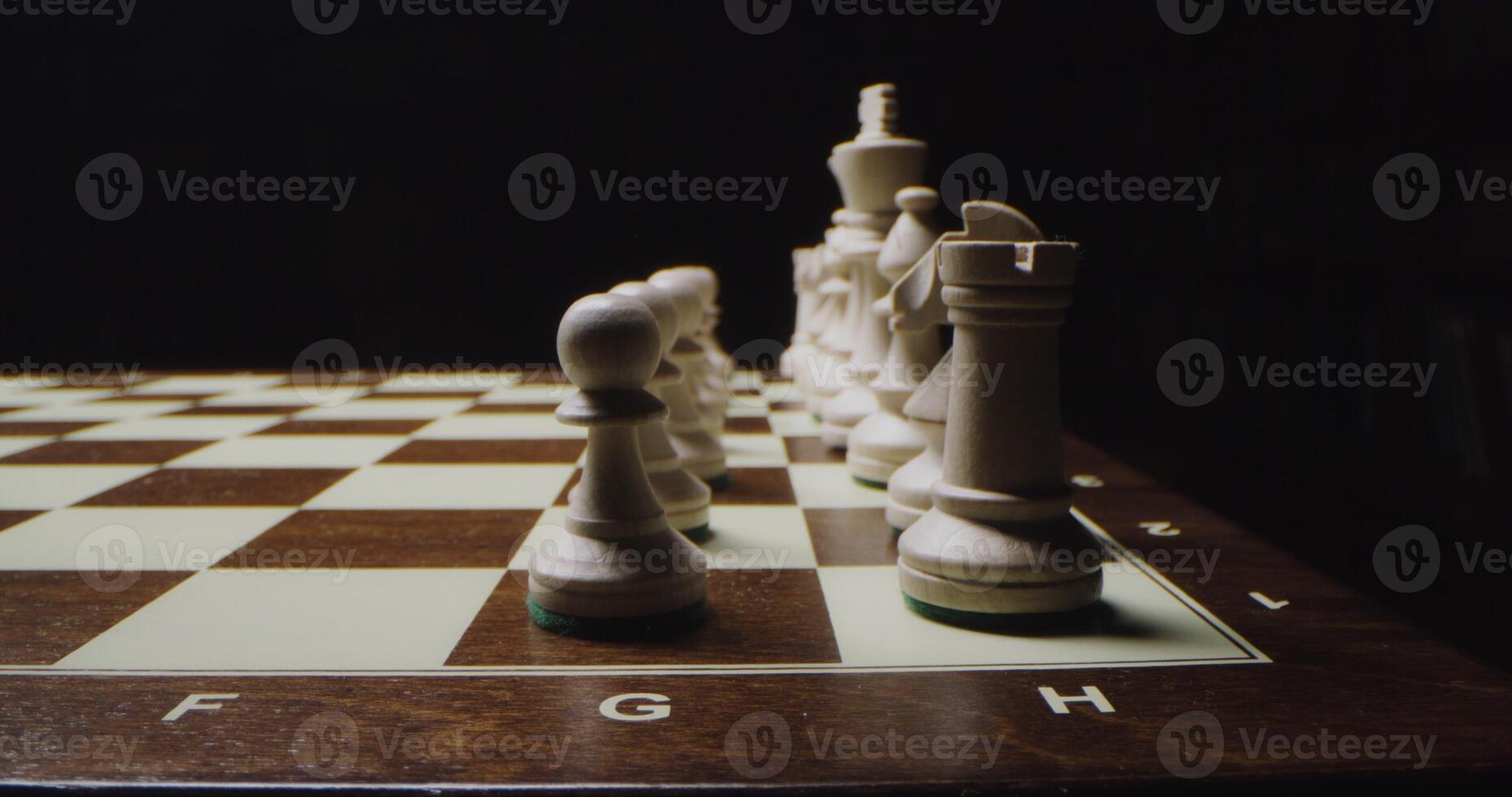 White chess pieces are lined up in even rows on a game board, ready for a game, close up photo